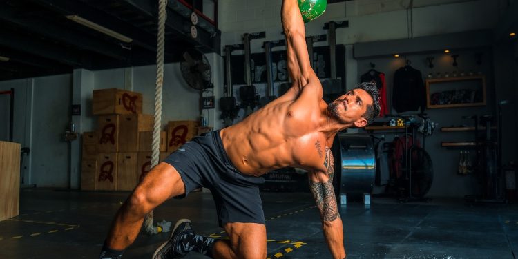 man in black shorts and black tank top doing push up