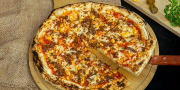 a pizza on a cutting board with a wooden spatula